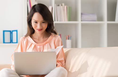 woman looking at her laptop on the couch