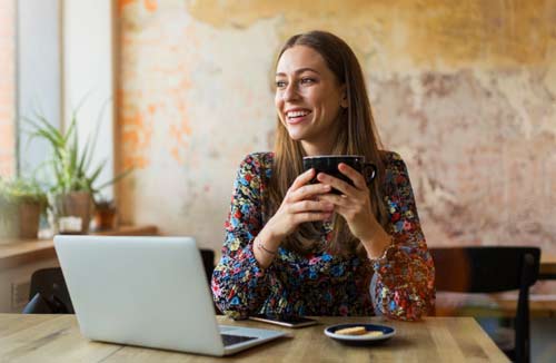 woman sipping coffee with her laptop in a cafe