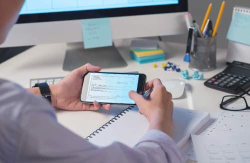 person looking at their smartphone deposited check image