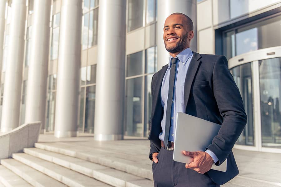A business man stands on the steps of a corporate building