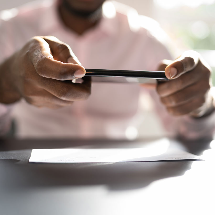 A man using his phone to take a photo of a check