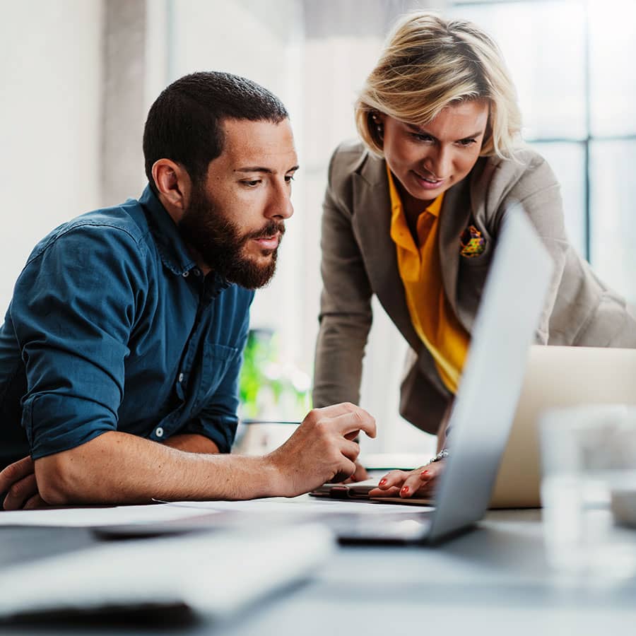 A man and woman at work looking at a laptop screen