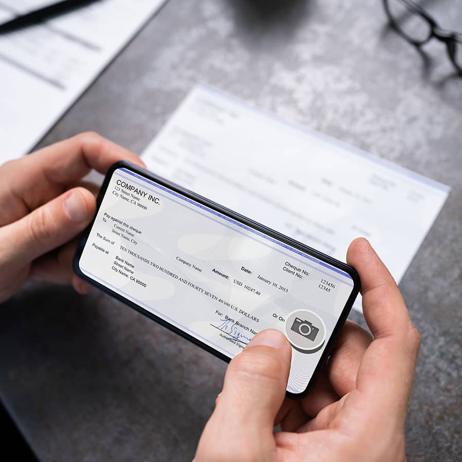 Closeup of hands on a phone taking a photo of a check