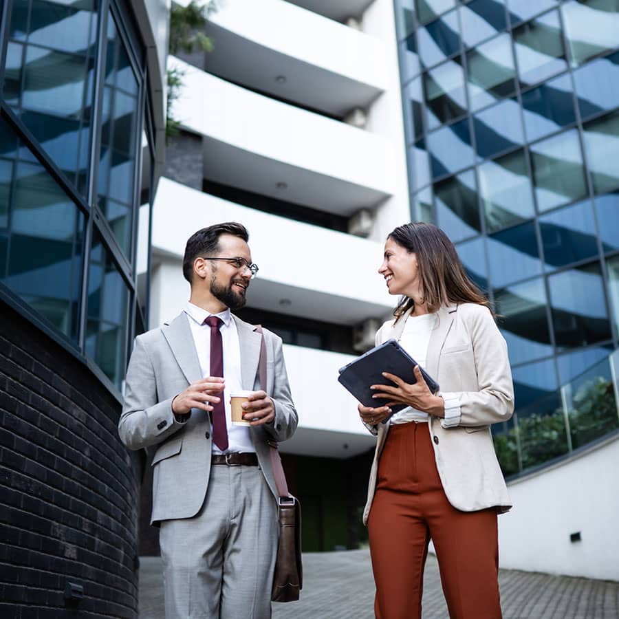 Two people walking between large skyscraper buildings