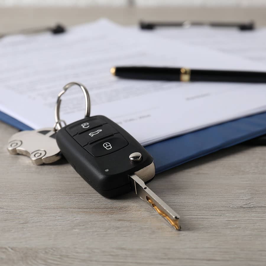 A car key fob on top of car loan documents