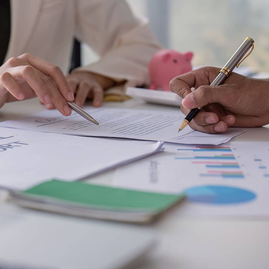 Two hands with pens signing documents
